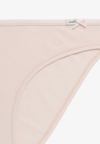 Jasnoróżowa bawełniana bielizna o gładkiej fakturze, z akcentem w postaci kokardki i metką z napisem "ATLANTIC" blisko pasa.