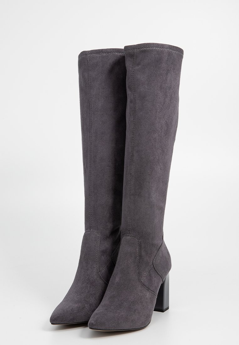 Stivali alti grigi in suede, con punta affusolata, tacco a blocco e dettagli di cucitura discreti lungo il gambale. Texture liscia in tutto.