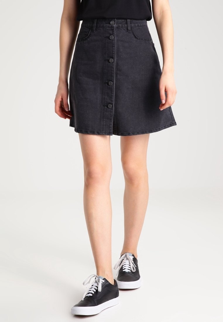 Zwarte denim rok met een uitlopende vorm, voorzien van een knopenrij aan de voorkant, zijzakken en een licht gestructureerde stofafwerking.