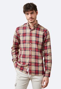 Camisa de cuadro de manga larga para hombre en beige, rojo y azul marino; presenta un collar abotonado y una tapeta frontal con botones blancos. Tejido de algodón suave.