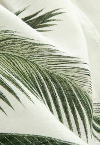 Fabric with a white background featuring green palm leaf patterns. The texture is lightweight, and the design emphasizes detailed leaf lines.