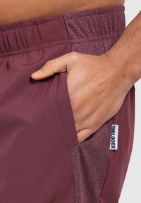 Burgunderfarbene Shorts mit texturiertem Bund, elastischem Sitz und seitlichen Taschen. Mit einem Markenetikett auf der Tasche. Glattes Material.