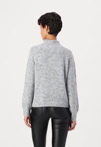 Gray, fuzzy knit sweater with a high collar and long sleeves. Features a relaxed fit and ribbed hem, paired with fitted black pants.