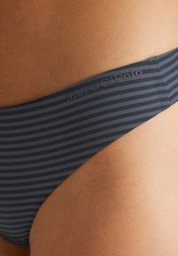 Bas de bikini rayé bleu marine fabriqué en matière lisse et extensible ; présente une ceinture de marque et une coupe basse élégante.