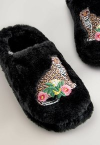Black fuzzy slippers with a textured finish. Features an embroidered leopard and floral design on the front. Soft and cozy material.
