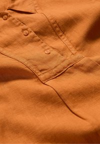 Oranje linnen shirt met een gestructureerd oppervlak, voorzien van zes knopen en een borstzak, met een casual, ontspannen ontwerp.