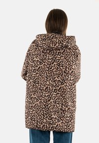 Abrigo con estampado de leopardo y capucha en tejido suave, diseño oversize, con un dobladillo que cae hasta medio muslo y mangas holgadas.