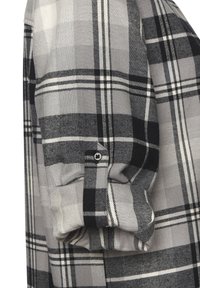 Camicia a quadri grigia e nera con polsini abbottonati, texture del tessuto morbida e linee della griglia bianche a contrasto.