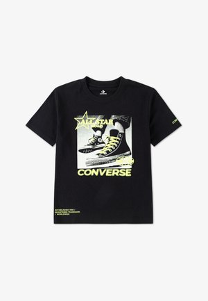 Zwart T-shirt met een grafisch ontwerp van hoge sneakers, met gele accenten en de tekst "ALL STAR" en "CONVERSE" in vetgedrukte letters.