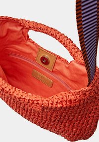 Sac à main tissé orange avec une surface texturée, un intérieur en tissu et une petite poche zippée. Accentué d'une bandoulière à rayures multiples.