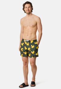 Zwemshorts in donkergroen met een patroon van gele rubberen eendjes, elastische tailleband met trekkoord en zijzakken. Geen zichtbare branding.
