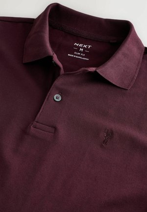 Burgundy slim fit poloshirt lavet af tekstureret stof med en tre-knaps stolpe og et broderet logo på venstre bryst.