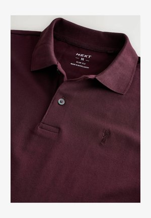 Burgundska polo majica slim fit kroja od teksturirane tkanine, s tri dugmeta na sprijeda i izvezenim logom na lijevoj strani prsnog koša.