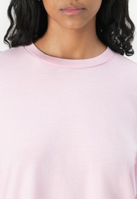 T-shirt rosa chiaro a maniche corte con scollo rotondo in tessuto morbido, caratterizzato da una vestibilità comoda e una texture liscia. Design semplice senza fantasie.