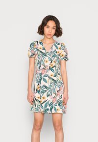 Vestido floral curto em tecido leve, com decote em V, mangas curtas bufantes e um padrão multicolorido de folhas e flores.