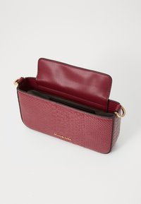 Burgundy faux snake leather bag with a smooth interior and gold hardware. Features a flap closure, compact rectangular shape, and side strap ring.