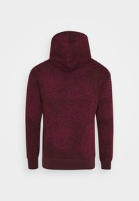 Bordeaux huppari, jossa on tekstuurinen abstrakti kuvio, pitkät hihat ja ribbaatut hihansuut sekä helma. Pehmeä kangas, rento istuvuus.