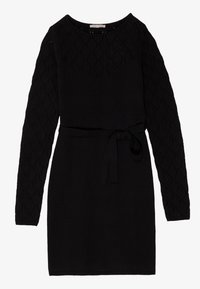 Black dress with long sleeves featuring a textured diamond pattern, cinched at the waist with a matching belt.