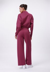 Bordeaux-rood bijpassend set bestaande uit een cropped pullover top en wijde broek, gemaakt van een gladde stof met een comfortabele pasvorm en elastische tailleband.