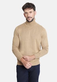 Suéter beige de cuello alto, hecho de un tejido suave, con mangas largas y puños acanalados, que presenta una silueta ajustada y una textura lisa.