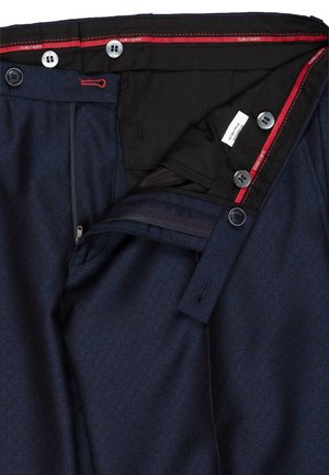 Marineblaue Hose mit einem dezenten geometrischen Muster, ausgestattet mit einem Reißverschluss, mehreren Knöpfen und roten Akzenten am inneren Bund.