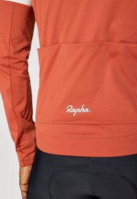 Rapha oranž cycling jersey pikkade varrukatega. Omab tagumist taskut ja valget logo. Sile tekstuur, disainitud soorituse ja mugavuse jaoks.