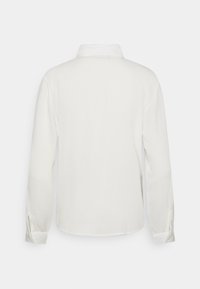 Vit långärmad skjorta med knappade manschetter, visad bakifrån mot en helt vit bakgrund.