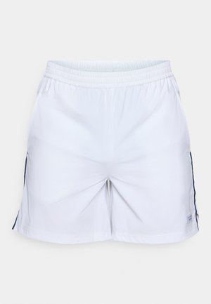 Hvite shorts laget av et lett materiale, med elastisk midjebånd og sidelommer. Har marineblå detaljer på sidene og en liten merkeetikett.