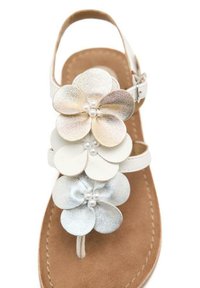 Sandal blanca con tres acentos metálicos en oro, blanco y plata. Plantilla suave en color marrón y correa de tobillo ajustable para un mejor ajuste.