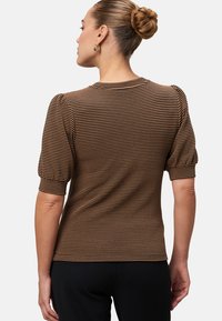 Haut à manches courtes à carreaux marron et crème avec un col rond. Présente des manches bouffantes plissées et une silhouette ajustée. Tissu en tricot texturé.