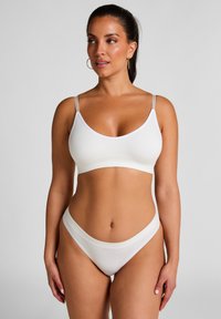 Weißes BH- und Bikini-Höschen-Set. Glatter Stoff, weiche Textur, dünne verstellbare Träger, V-Ausschnitten und niedrige Taille mit minimaler Abdeckung.