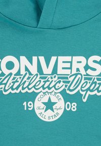 Τιρκουάζ φούτερ με κουκούλα με λευκό κείμενο που γράφει "CONVERSE Athletic Dept" και κυκλικό λογότυπο με αστέρι. Μαλακό ύφασμα, κανονική εφαρμογή και σχεδιασμός με κουκούλα.