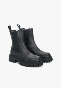 Černé kožené kotníkové boty s elastickými bočními panely, masivní gumovou podrážkou a poutky pro snadné obouvání. Elegantní design s matným povrchem.