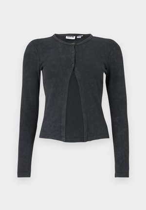 Μαύρη ριμπ μακρυμάνικη κοντή ζακέτα με στρογγυλή λαιμόκοψη και δύο κουμπιά στο μπροστινό μέρος, ελαφρώς ανοιχτή στο κέντρο.