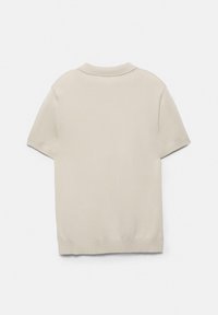 Maglia beige a maniche corte in maglia con un colletto semplice, visualizzata stesa con la parte posteriore rivolta verso l'alto su uno sfondo bianco.