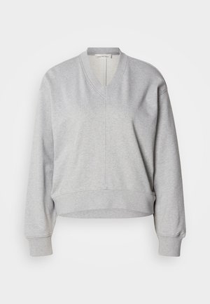 Hall hall pusa, millel on V-kaelus, pikad varrukad ja soonilised mansetid. Valmistatud pehmest kangast, esiküljel õmblus ning lühendatud lõige.