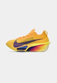 Nike futócipő élénk narancssárga színben, lila akcentusokkal. Könnyű hálós felsőrész, ívelt talp multiszínű átmeneti mintával.