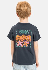 Camiseta de color azul oscuro con un gran gráfico multicolor en la parte trasera que presenta plantas y flores tropicales, hecha de un suave material de algodón.