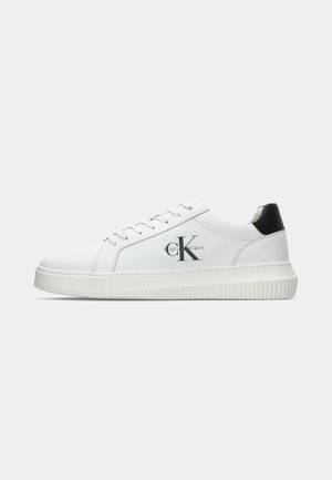 Witte lage sneakers met zwarte hieltab, vetersluiting aan de voorkant, dikke zool en Calvin Klein-logo aan de zijkant.