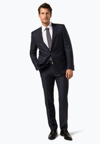 Marineblauer Anzug mit taillierter Passform, ausgestattet mit einem einreihigen Sakko, mit Revers und passender Hose. Tragen Sie dazu ein weißes Hemd und eine graue Krawatte.
