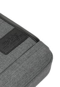 Šedý látkový doplněk s texturovaným povrchem, který obsahuje černou koženou nášivku s embosovaným nápisem "relaks" a elegantní, moderní design.