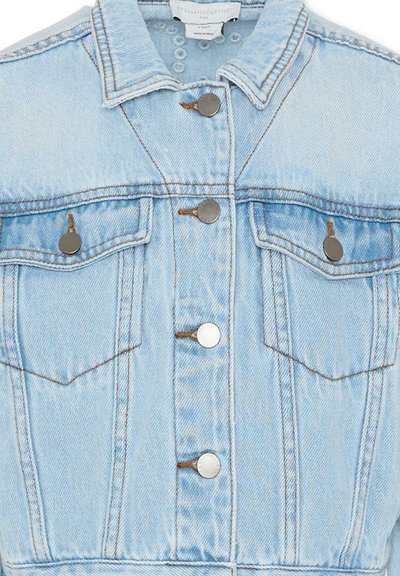 Veste en jean bleu clair avec fermeture à boutons, deux poches poitrine à rabat et boutons, et coutures visibles marron.