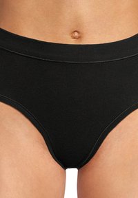 Zwarte high-waisted slip gemaakt van zachte, elastische stof. Heeft een gladde textuur met platte naden voor comfort en minimale zichtbaarheid onder kleding.
