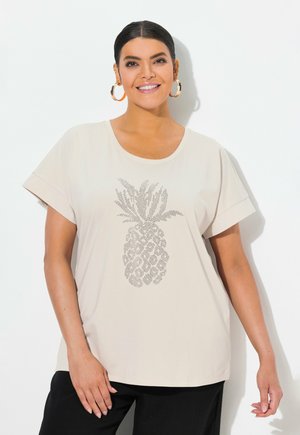T-shirt beige a maniche corte con una grafica di un ananas puntinato. Tessuto morbido e vestibilità rilassata. Abbinato a pantaloni neri.