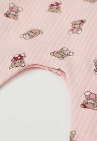 Růžová pruhovaná tkanina obsahuje opakující se karikaturní medvídky v různobarevném oblečení a doplňcích, což vytváří hravý vzor.