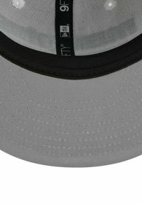 Graue Baseballkappe mit schwarzem Schirm, ausgestattet mit einem strukturierten Stoff, genähten Details und einem Innenetikett, das Marken- und Stilinformationen zeigt.