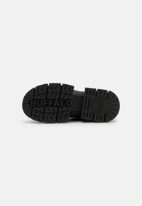 Talpă de cauciuc neagră cu un model adânc de profil. Logo-ul „BUFFALO” embosat în centrul talpii. Detaliu circular al logo-ului aproape de călcâi.