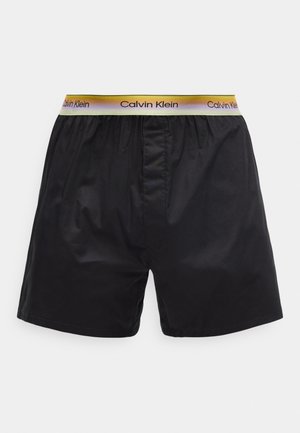 Pánské černé boxerky s barevným páskem se značkou Calvin Klein na neutrálním pozadí.