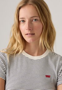 Raidallinen lyhythihainen T-paita, jossa on ribbikuvio, vaalea pohja ja laivastonsiniset raidat. Rinnassa pieni punainen Levi's-logo.