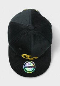 Mustat veluurikypärä, jossa on etupuolella voimakas keltainen brodeeratun logon ja visorin holografinen tarra.